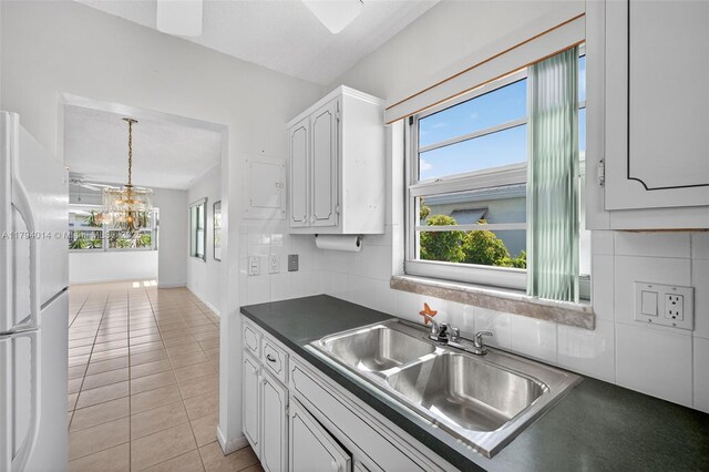 401 S Golf Blvd Unit 270, Pompano Beach, FL 33064 - kitchen with freestanding refrigerator, dark countertops, white cabinetry, a chandelier, and tasteful backsplash