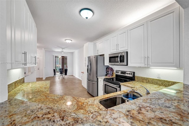 7715 Southampton Ter Unit 110, Tamarac, FL 33321 - kitchen featuring a textured ceiling, appliances with stainless steel finishes, a sink, light stone counters, and white cabinets