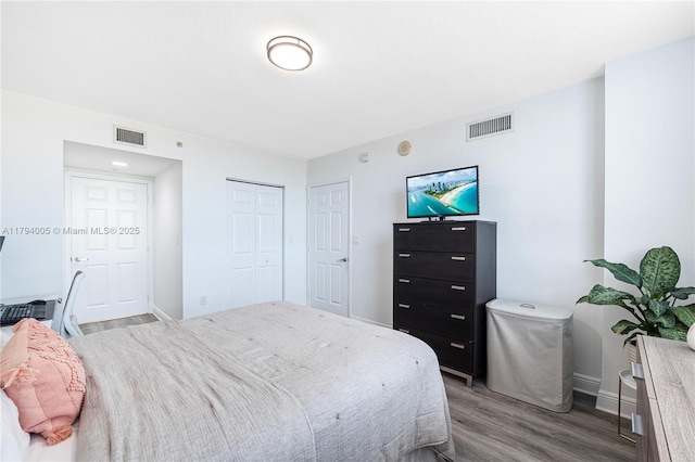 bedroom featuring visible vents, baseboards, wood finished floors, and a closet