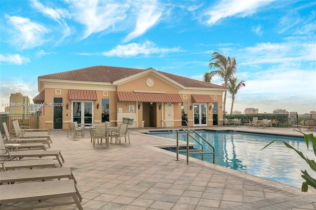 pool with french doors, fence, and a patio