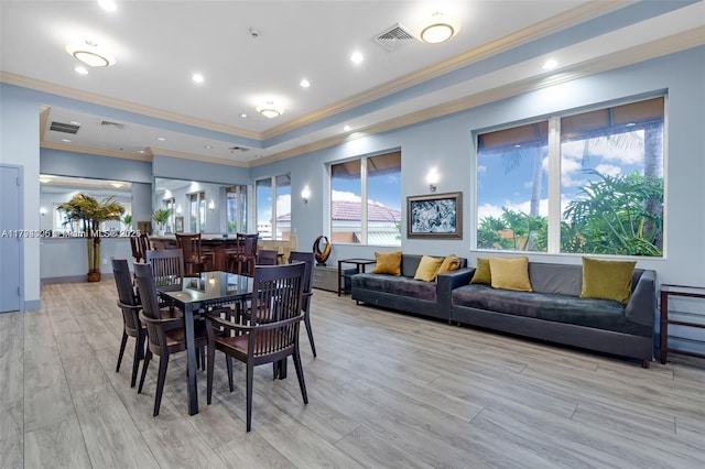dining space with visible vents, ornamental molding, and light wood-style flooring