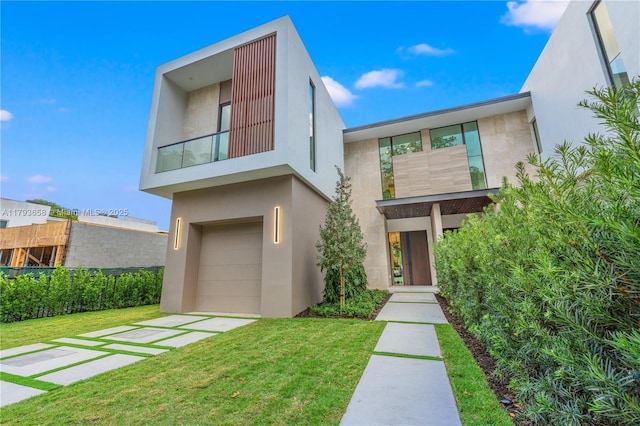 contemporary house with a garage, stucco siding, and a front lawn