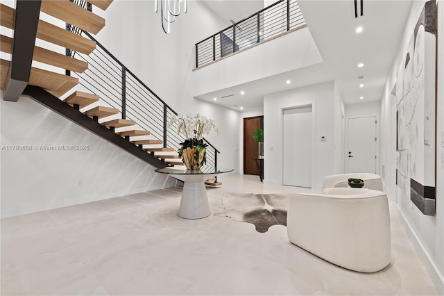 entryway featuring a high ceiling, finished concrete flooring, stairs, recessed lighting, and baseboards