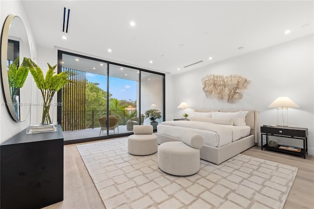 bedroom featuring access to outside, recessed lighting, light wood-style flooring, and expansive windows