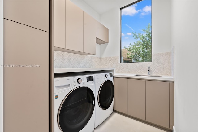 clothes washing area with cabinet space, separate washer and dryer, and a sink
