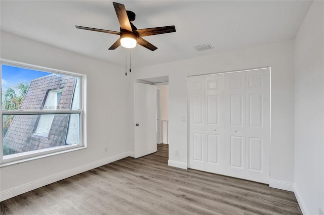 unfurnished bedroom featuring wood finished floors, baseboards, a closet, and a ceiling fan
