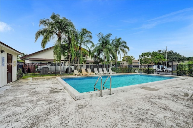 community pool with fence and a patio area