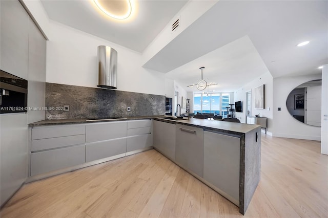 16001 Collins Ave Unit 707, Sunny Isles Beach, FL 33160 - kitchen featuring dark countertops, a peninsula, a sink, light wood-style floors, and open floor plan