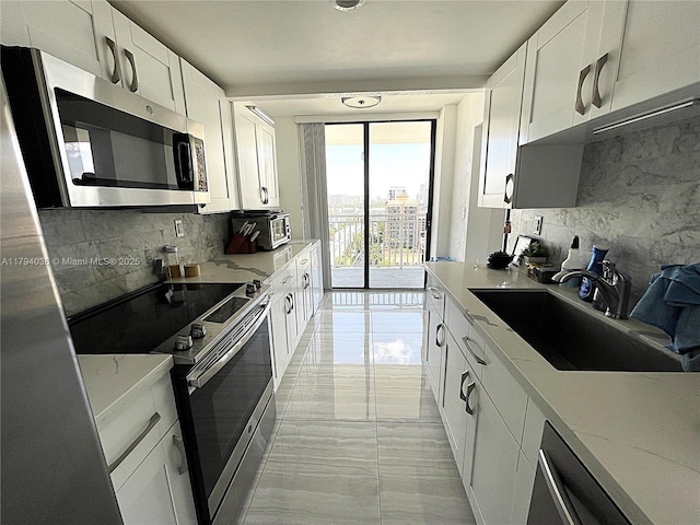 kitchen with a sink, decorative backsplash, white cabinetry, and stainless steel appliances