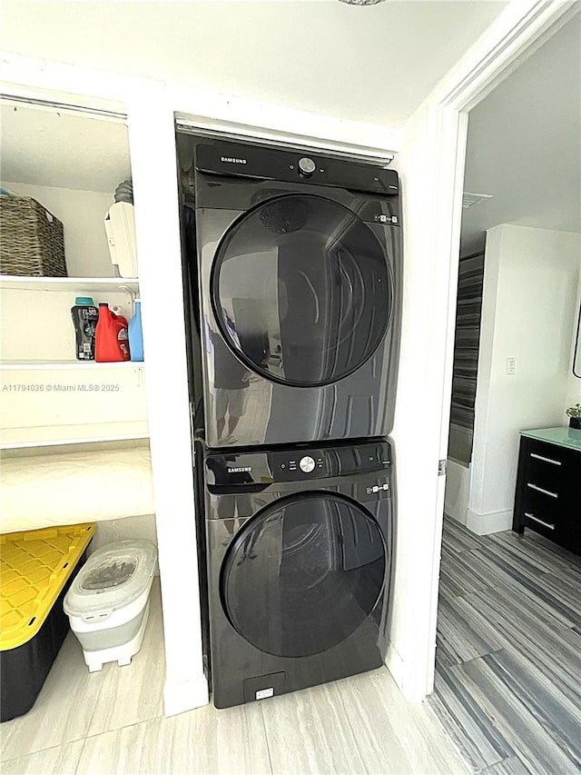 clothes washing area featuring laundry area, baseboards, and stacked washing maching and dryer