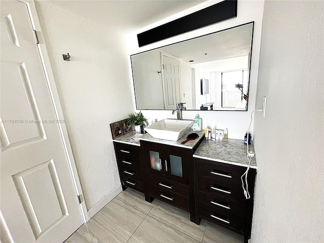 bathroom with vanity, baseboards, a textured wall, and tile patterned flooring