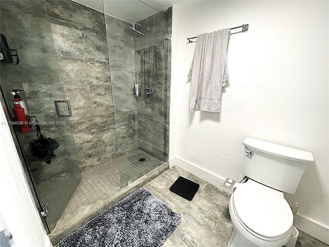 bathroom with baseboards, a shower stall, and toilet