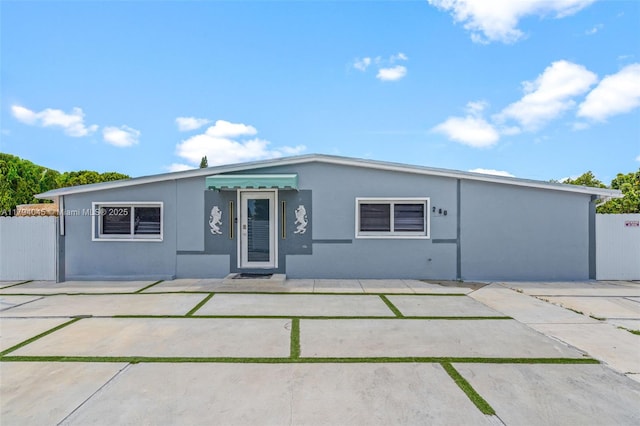 view of front facade featuring stucco siding, a patio area, and fence