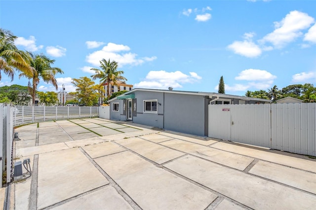 exterior space featuring fence, a gate, stucco siding, and a patio area