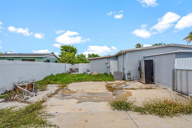 back of property with fence, stucco siding, central AC, and a patio area