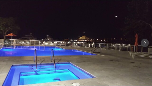 1581 Brickell Ave Unit 1807, Miami, FL 33129 - pool at night with a community pool, a patio area, fence, and a community hot tub