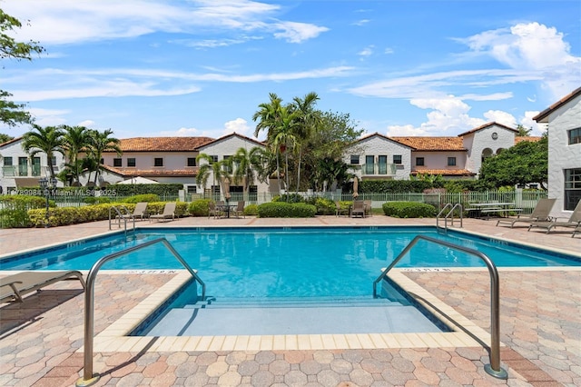 community pool featuring a patio area, fence, and a residential view