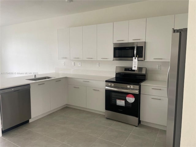 kitchen featuring light countertops, a sink, appliances with stainless steel finishes, and light tile patterned floors