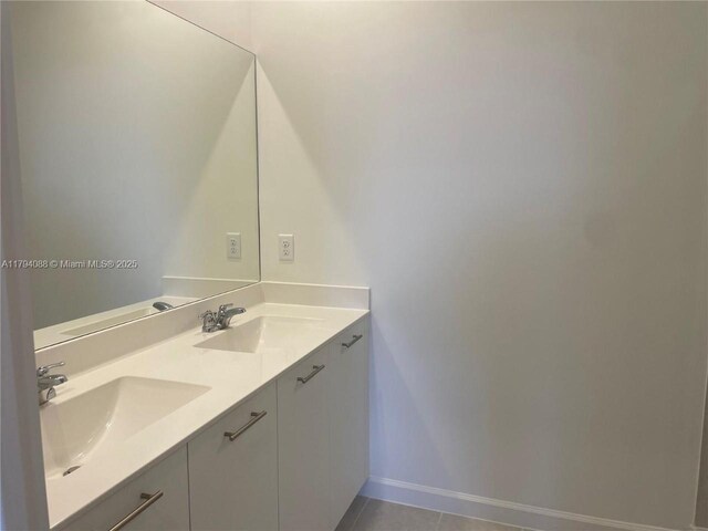 bathroom with a sink, baseboards, tile patterned floors, and double vanity