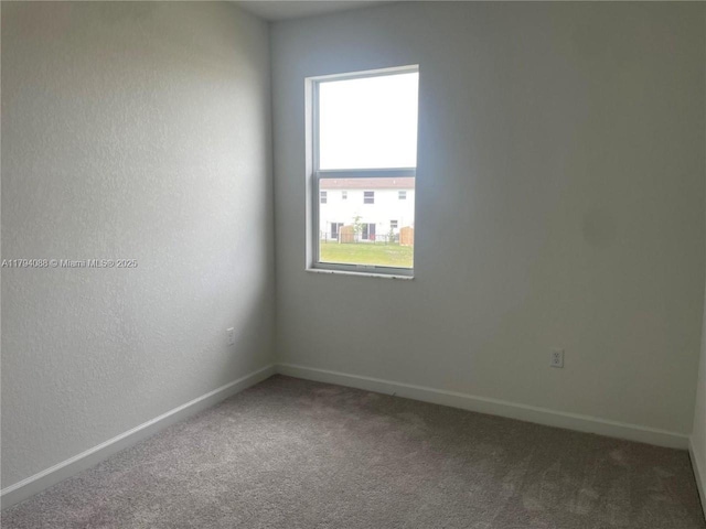 carpeted spare room featuring baseboards