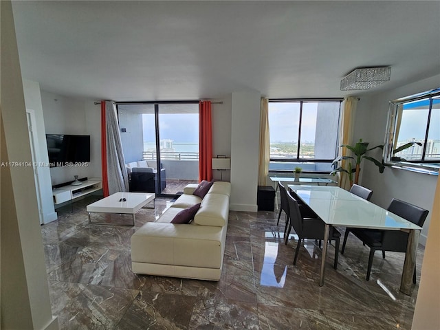 living area with baseboards, plenty of natural light, and marble finish floor