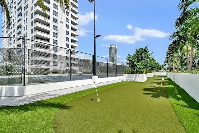 view of property's community with fence and a tennis court