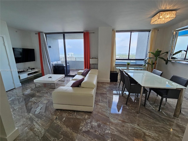 living area with baseboards, a wall of windows, and marble finish floor