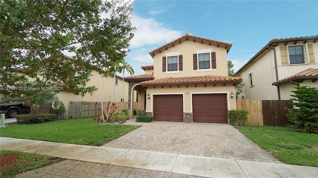 mediterranean / spanish-style house featuring fence, decorative driveway, stucco siding, a tiled roof, and an attached garage