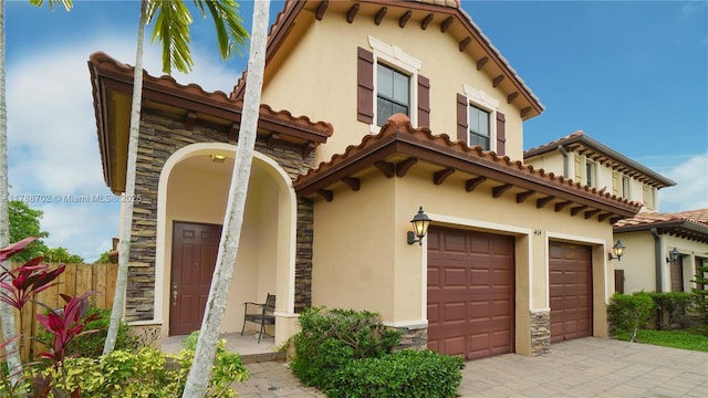 mediterranean / spanish home with a garage, stone siding, and stucco siding