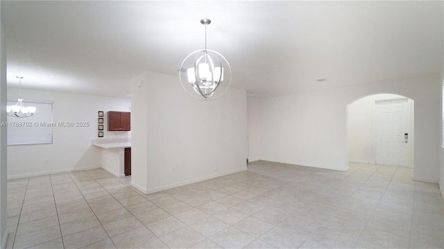 unfurnished room featuring arched walkways, light tile patterned flooring, and a chandelier