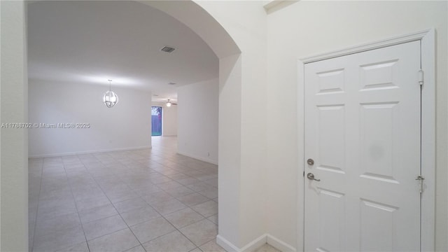 hallway featuring arched walkways, baseboards, visible vents, and light tile patterned flooring