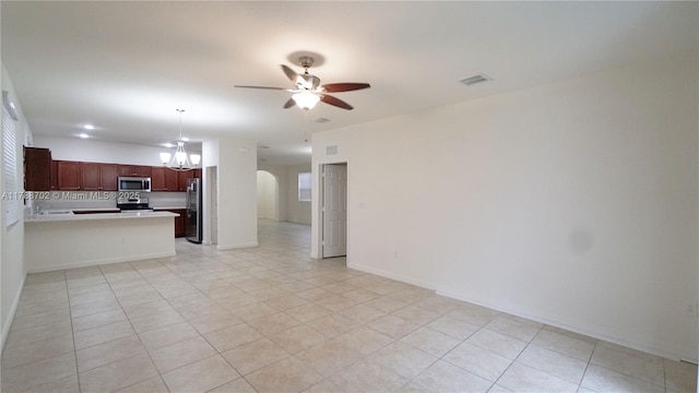unfurnished living room featuring arched walkways, ceiling fan with notable chandelier, light tile patterned flooring, and visible vents