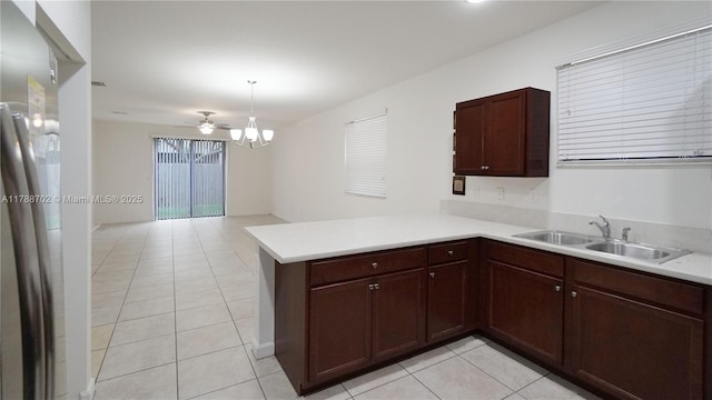 kitchen featuring light tile patterned floors, light countertops, a sink, a peninsula, and open floor plan