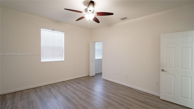 spare room featuring visible vents, baseboards, ceiling fan, and wood finished floors