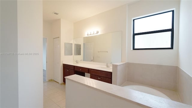 full bathroom with a sink, a bath, tile patterned flooring, and double vanity