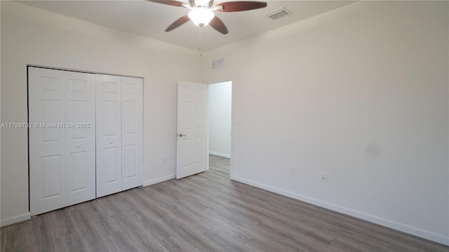 unfurnished bedroom with visible vents, wood finished floors, and a closet