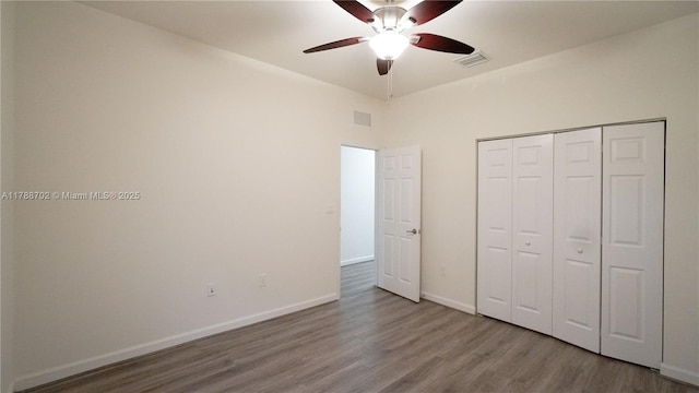 unfurnished bedroom featuring baseboards, visible vents, wood finished floors, and a closet