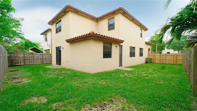 back of house with a lawn, a fenced backyard, stucco siding, and a tile roof