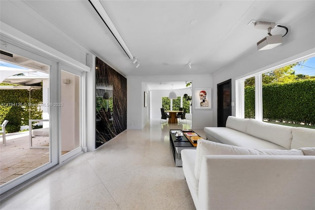 living area featuring baseboards, track lighting, and light speckled floor