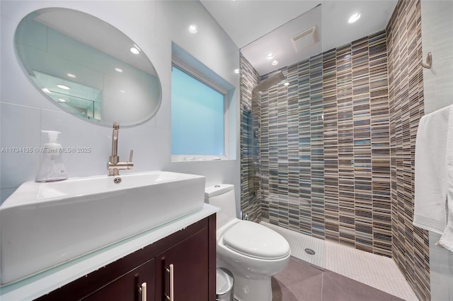 bathroom with vanity, a tile shower, toilet, and visible vents