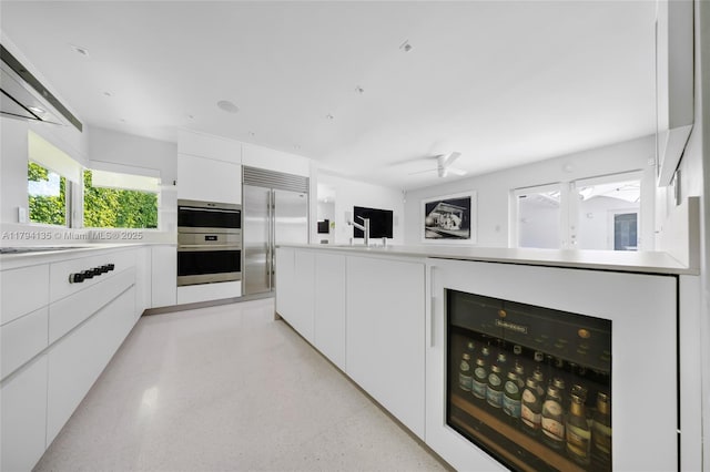 kitchen featuring light countertops, beverage cooler, white cabinetry, stainless steel appliances, and modern cabinets