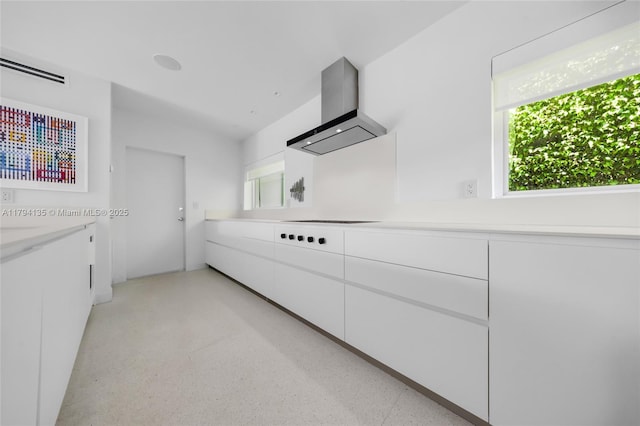 kitchen featuring visible vents, black electric cooktop, light countertops, white cabinetry, and wall chimney exhaust hood