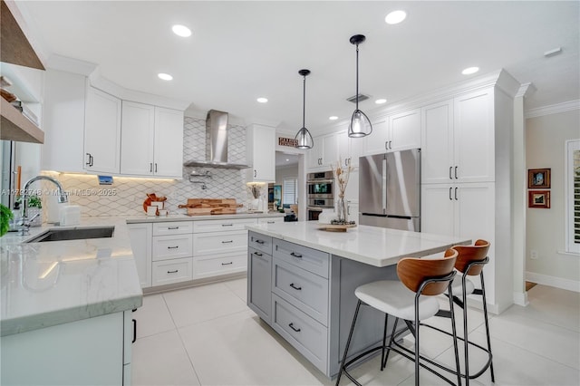 kitchen featuring wall chimney range hood, crown molding, a sink, stainless steel appliances, and backsplash
