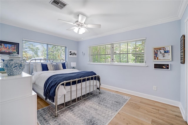 bedroom with light wood-style floors, baseboards, ornamental molding, and visible vents