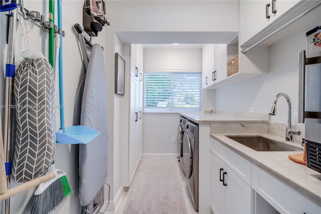 washroom featuring a sink, baseboards, cabinet space, and independent washer and dryer