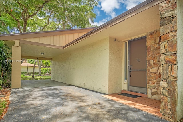 8097 Royal Palm Cir, Tamarac, FL 33321 - view of exterior entry with a carport, a patio area, stone siding, and stucco siding