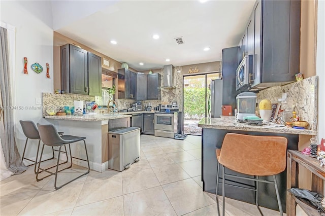 8097 Royal Palm Cir, Tamarac, FL 33321 - kitchen with wall chimney range hood, appliances with stainless steel finishes, a peninsula, decorative backsplash, and visible vents