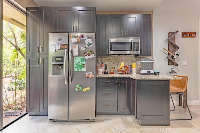 8097 Royal Palm Cir, Tamarac, FL 33321 - kitchen featuring light tile patterned floors, appliances with stainless steel finishes, backsplash, and light stone counters