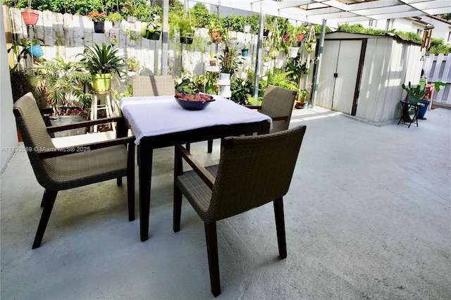 view of patio with a storage shed, fence, an outdoor structure, and outdoor dining area
