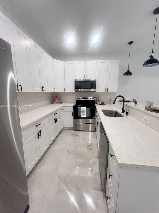 920 E Barton St, Lehigh Acres, FL 33974 - kitchen featuring stainless steel appliances, a sink, light marble finish flooring, white cabinetry, and decorative light fixtures